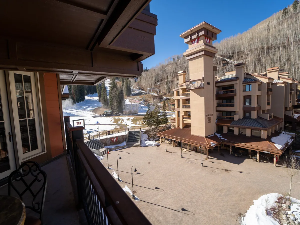A cozy balcony at Purgatory Lodge overlooking the breathtaking snowy mountain landscape, with the lodge's architecture in view. The setting suggests ease of access to winter activities and opportunities for relaxation after a day on the slopes.