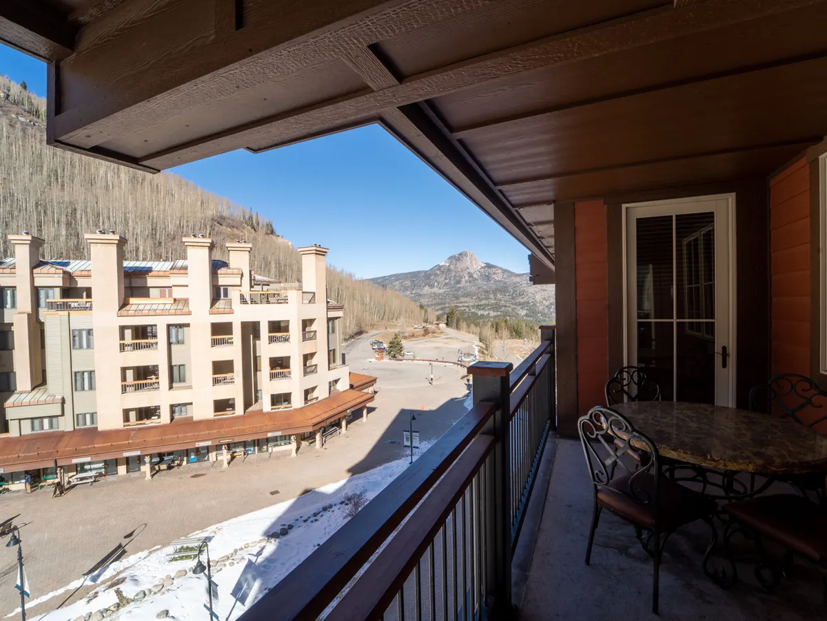 A private balcony with comfortable seating overlooking spectacular mountain views and the surrounding buildings. The scene is perfect for enjoying morning coffee, sunset gazing, or entertaining guests in a serene alpine setting.