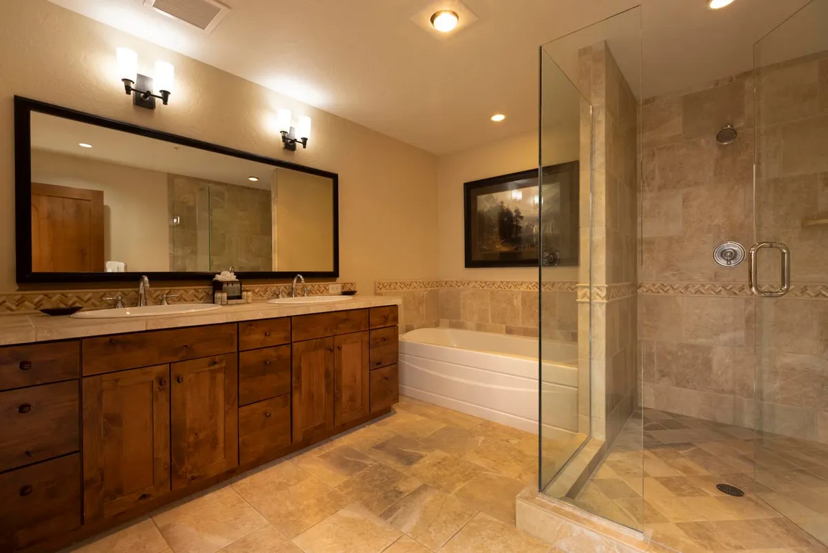 A luxurious bathroom showcasing a double sink vanity, a modern glass shower enclosure, and a freestanding bathtub. The neutral tones and elegant fixtures evoke a spa-like atmosphere for relaxation and self-care.