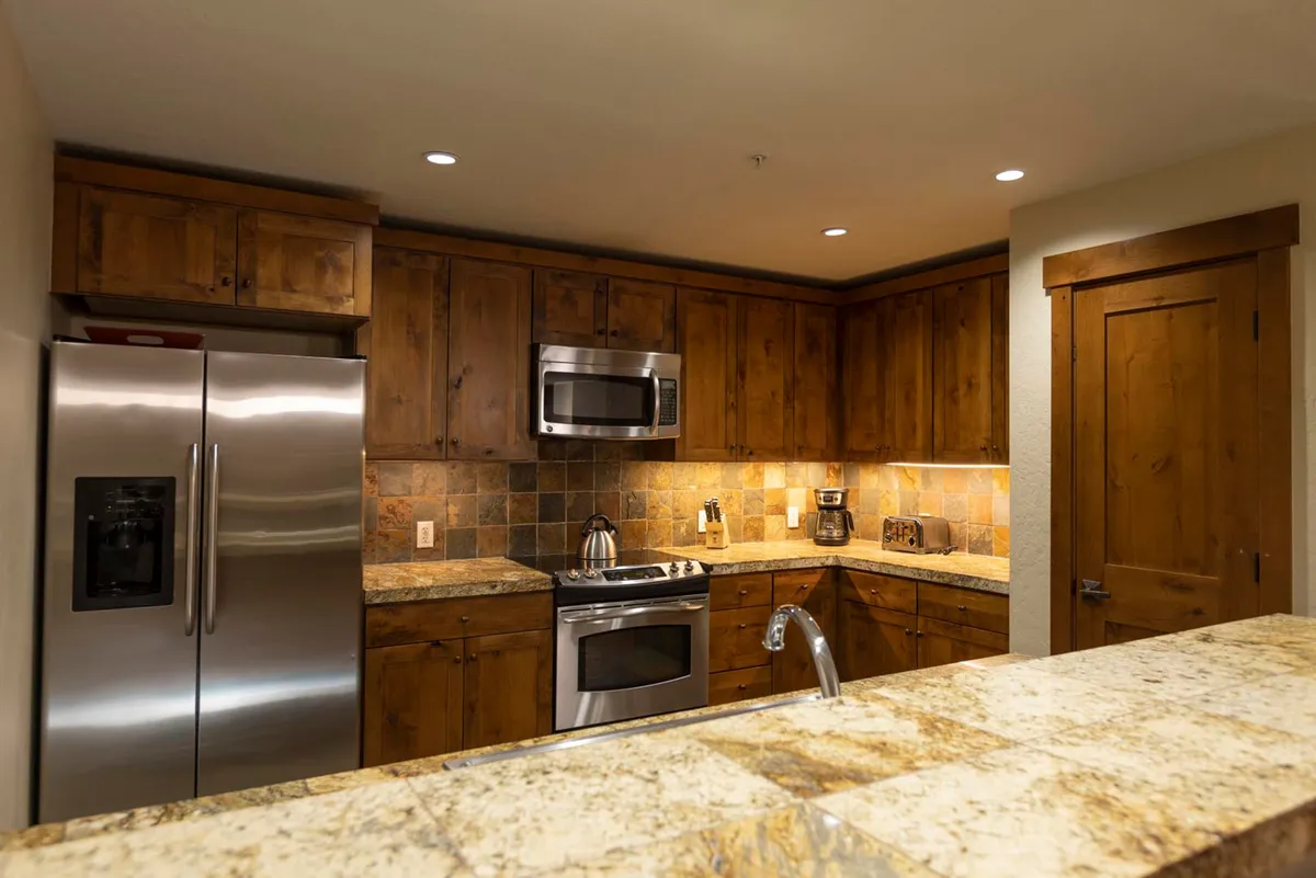A modern kitchen with stainless steel appliances, granite countertops, and wooden cabinetry. The space is set up for cooking, entertaining, and family gatherings, hinting at activities like making holiday cookies or hosting brunch.