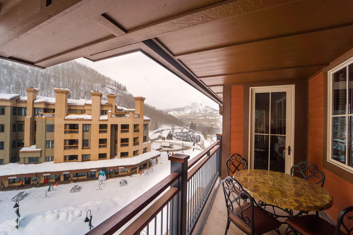 A private balcony with seating, overlooking a serene, snow-covered mountain landscape. The view offers a tranquil setting, ideal for enjoying the fresh alpine air and panoramic vistas in any season.